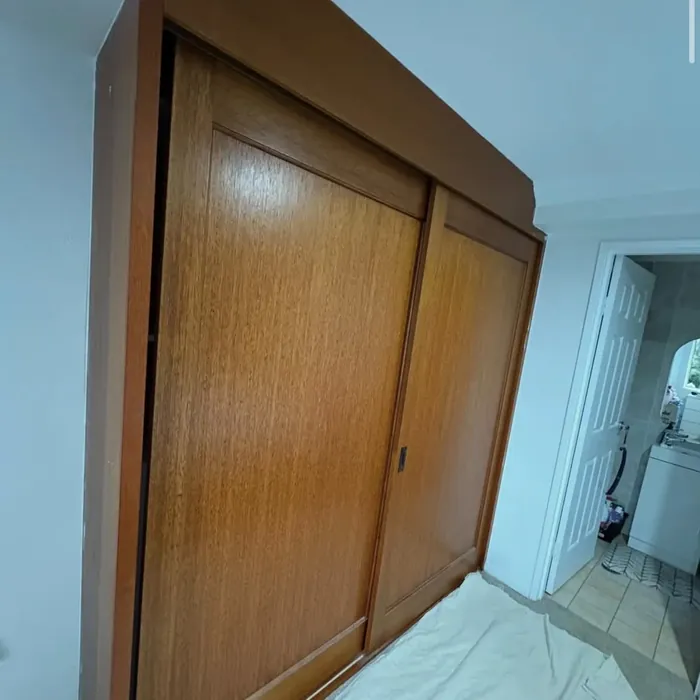 Built-in wardrobe with varnished timber sliding doors and matching timber surround.