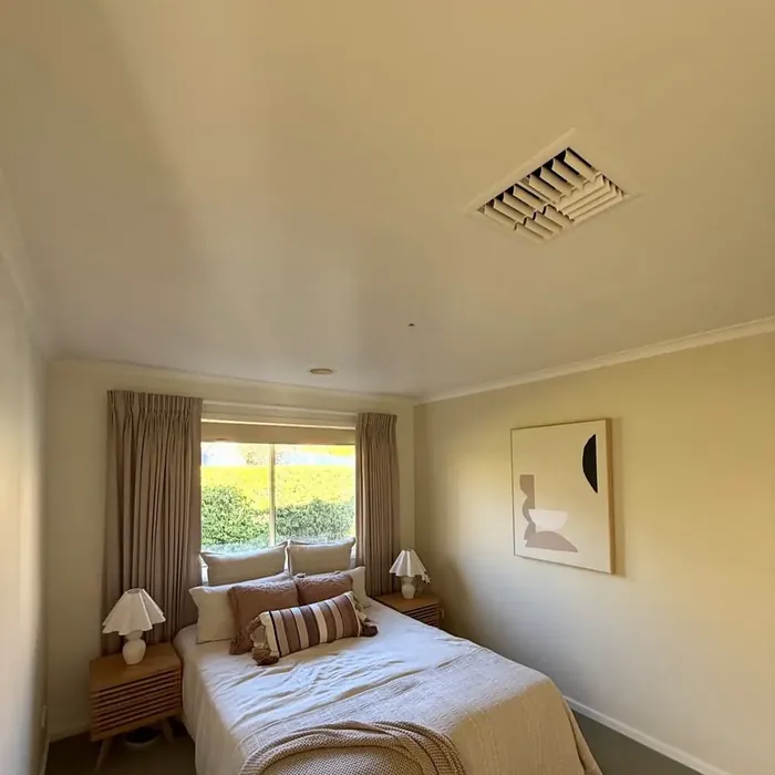 The same bedroom after painting: an even, clean ceiling above warm neutral walls.
