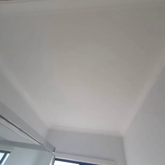 The same bathroom ceiling after sealing and repainting: uniform white, no trace of the stain.