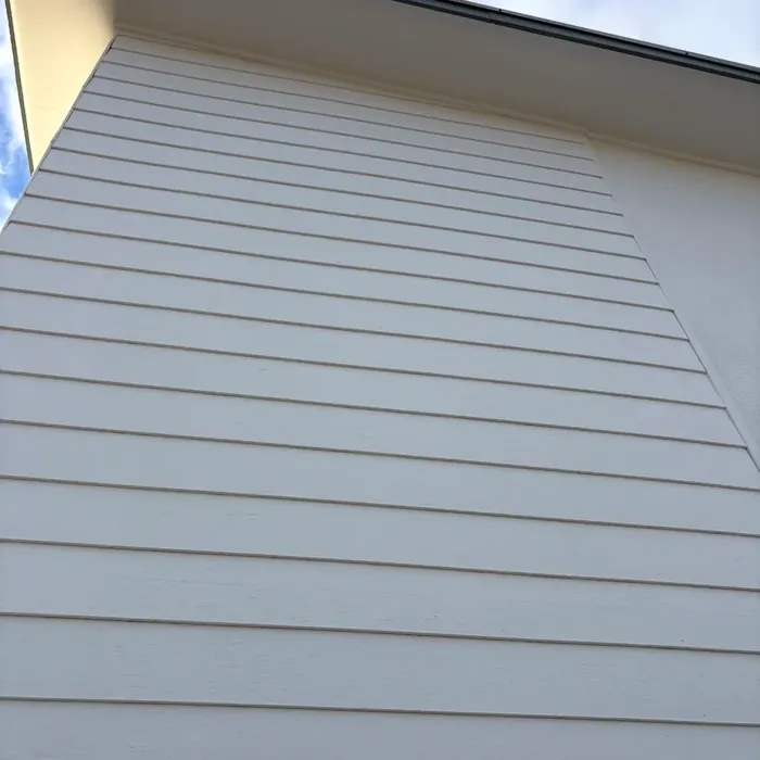The same gable end after painting: clean, even weatherboard cladding.