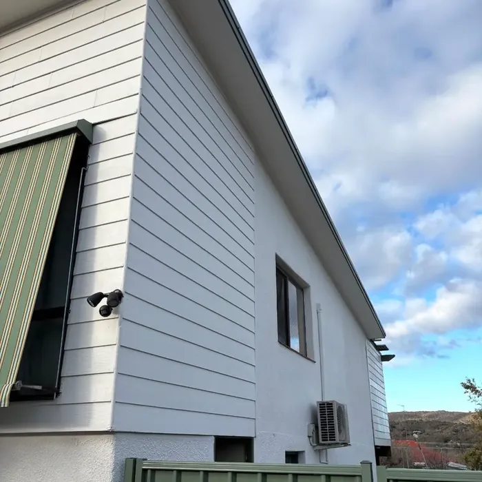 The same rear wall repainted clean and even, with the air conditioning unit and gable above.