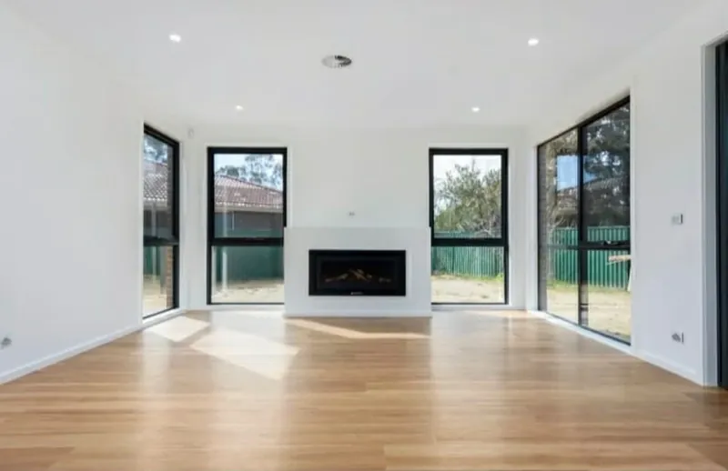Open plan living room with white walls, a gas fireplace and full-height windows.