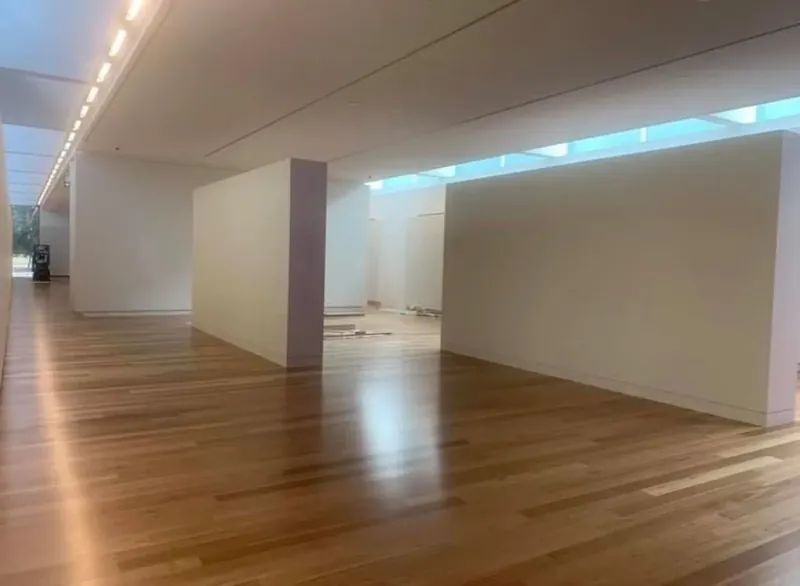 Long gallery corridor with finished white walls and a continuous cove light.