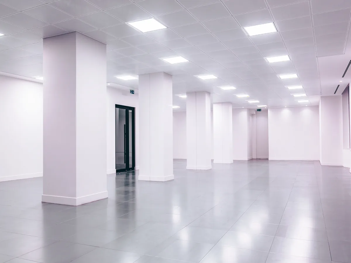 Large empty commercial floor with white columns, white walls and a polished tiled floor.