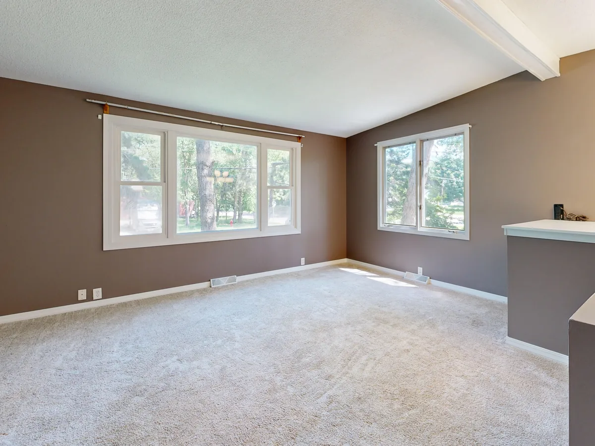 Living room repainted in warm taupe with crisp white trim and a textured white ceiling.