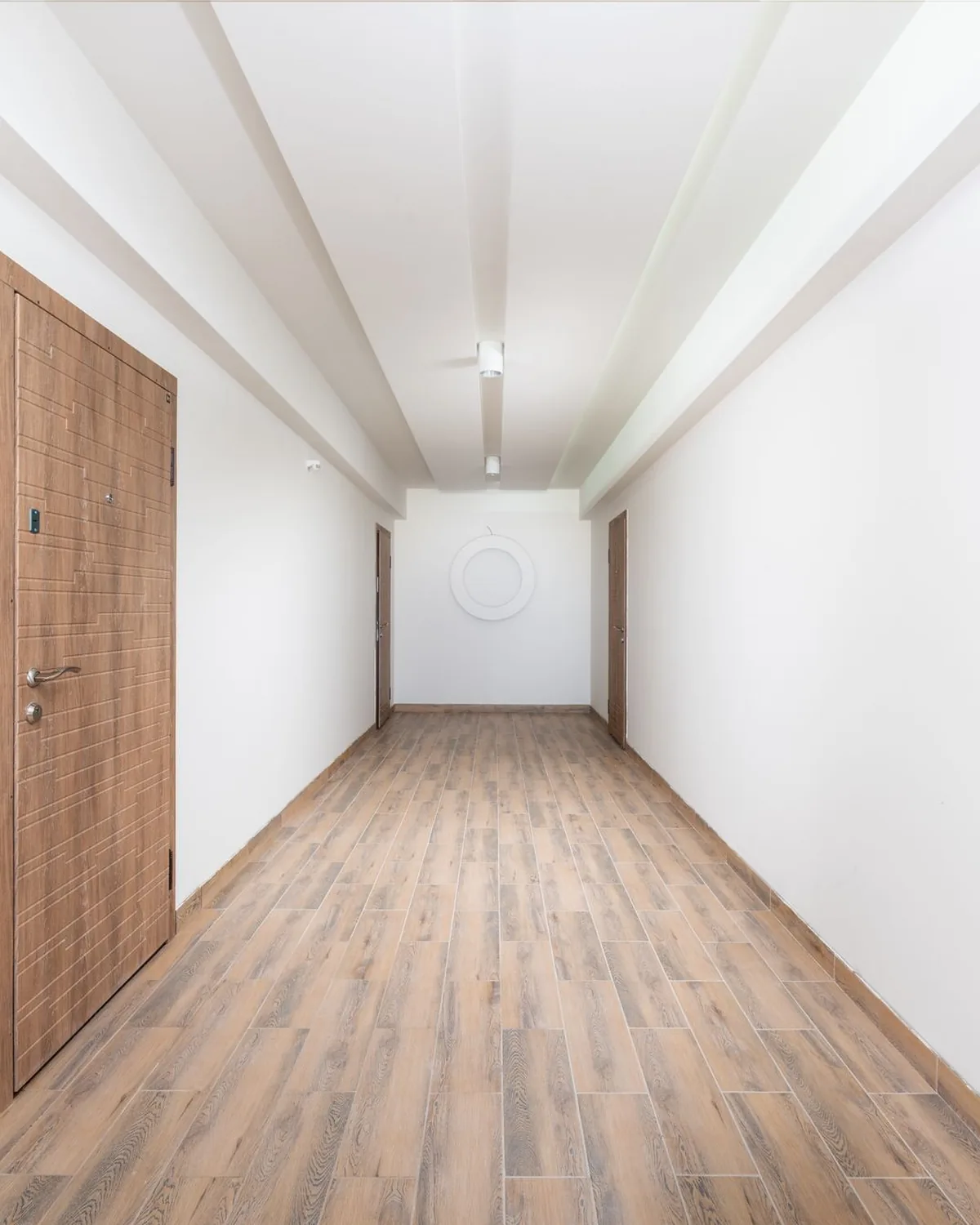 Hallway with white painted walls, a timber door and a timber floor.